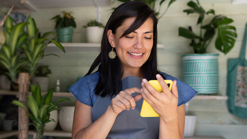 Woman using cell phone in gardening store