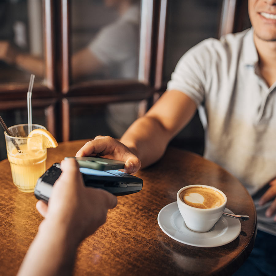 Hombre pagando con su celular en un café